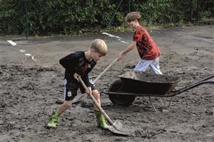 Do úklidu po velké vodě se zapojili všichni. Na snímku kluci pomáhají odklízet bahno, které rozvodněná Lubinka nanesla na parkoviště před obchodem v Mniší. FOTO: DAVID MACHÁČEK