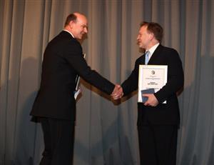 Starosta města Josef Jalůvka přebírá z rukou náměstka ministra vnitra cenu za kvalitu a inovaci ve veřejné správě. Kopřivnice již podruhé obhájila stříbrný stupeň. 
FOTO: ARCHIV
