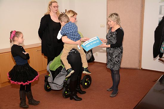Maminka Matúška převzala z rukou místostarostky Rysové šek určený na rehabilitační kůru svého syna. Menší polovinu částky vynesla tradiční sbírka plastových vršků.  
FOTO: D. MACHÁČEK
