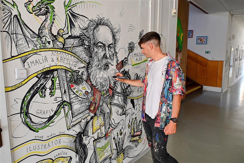 Hynek Tekula dokončuje práci na kusu nástěnné malby věnované Mikuláši Alšovi, která nově zdobí chodby místní základní školy nesoucí jeho jméno.