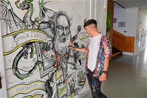 Hynek Tekula dokončuje práci na kusu nástěnné malby věnované Mikuláši Alšovi, která nově zdobí chodby místní základní školy nesoucí jeho jméno.